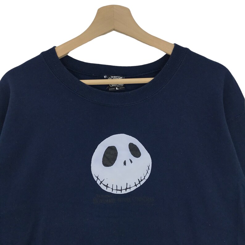K&ouml;nnte beinhalten: Ein marineblaues Sweatshirt mit einem wei&szlig;en Aufdruck von Jack Skellingtons Gesicht aus dem Film "Nightmare Before Christmas".