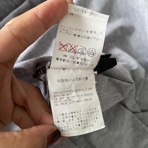 Puede incluir: Una etiqueta de cuidado de prenda de tela blanca con texto negro y s&iacute;mbolos de lavado rojos. La etiqueta incluye el c&oacute;digo LZ-T43-037, instrucciones en japon&eacute;s y texto en ingl&eacute;s: Specially-printed material is used. Dryclean only. The print may peel off by repeated dry-cleaning. Use press cloth when ironing.