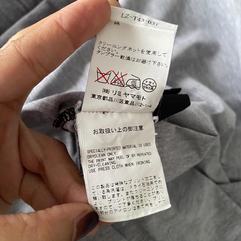 Puede incluir: Una etiqueta de cuidado de prenda de tela blanca con texto negro y s&iacute;mbolos de lavado rojos. La etiqueta incluye el c&oacute;digo LZ-T43-037, instrucciones en japon&eacute;s y texto en ingl&eacute;s: Specially-printed material is used. Dryclean only. The print may peel off by repeated dry-cleaning. Use press cloth when ironing.