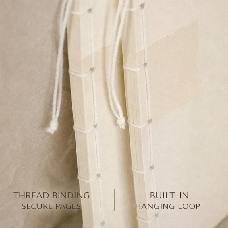 Pu&ograve; includere: Primo piano di un taccuino color crema con rilegatura a filo e un anello per appenderlo integrato. Le pagine del taccuino sono fissate con filo. Il testo a sinistra recita "THREAD BINDING SECURE PAGES" e a destra "BUILT-IN HANGING LOOP".