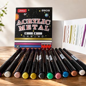 Peut inclure: Un ensemble de 12 marqueurs acryliques métalliques JiMiao 8808 dans une boîte noire avec des graphismes sur le thème de l'espace. La boîte affiche le texte ACRYLIC METAL et inclut une carte d'échantillons montrant des lignes ondulées et droites dans diverses couleurs métalliques. Douze marqueurs noirs sont alignés devant la boîte, chacun doté d'un capuchon coloré correspondant à la teinte de l'encre.