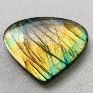 May include: A triangular, iridescent labradorite gemstone with a yellow and green color pattern.