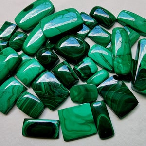 May include: A collection of 20 green malachite cabochons, each with a unique pattern of veins and swirls. The stones are smooth and polished, with a glossy finish. They are ideal for jewellery making or other craft projects.