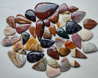 May include: A collection of 30 agate cabochons in various colors and patterns, including red, brown, white, yellow, green, and black. The cabochons are all teardrop shaped and have a smooth, polished finish.