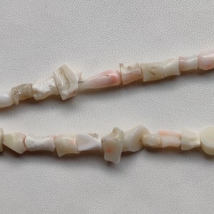May include: A strand of pink and white coral beads. The beads are irregular in shape and size, and some have a natural, rough texture.