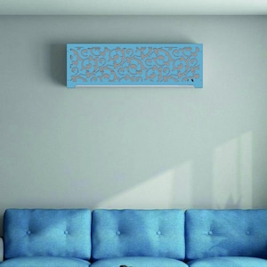 May include: A blue decorative wall panel with a floral design is mounted on a grey wall. The panel is rectangular and has a cutout pattern. Below it is a blue sofa with a white coffee table.