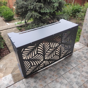 May include: A rectangular metal radiator cover featuring a matte grey finish and a laser-cut pattern of stylised leaves. The structure includes a solid top surface with a narrow horizontal slot and side panels secured with visible metal fasteners.