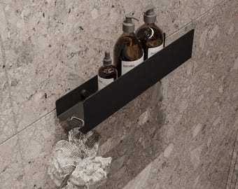 May include: Black metal shelf with three bottles of liquid soap and a mesh bath pouf hanging from the bottom. The bottles are labeled "meraki".