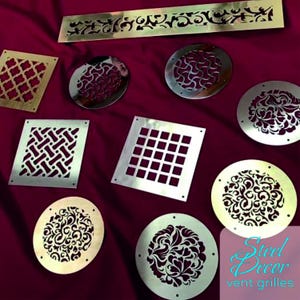 Op de afbeelding: Een assortiment van decoratieve metalen ventilatieroosters in verschillende vormen en ontwerpen. De roosters zijn gemaakt van gepolijst metaal met ingewikkelde uitsnijdingen. De roosters worden getoond op een rode stoffen achtergrond. De tekst "Steel Decor vent grilles" is zichtbaar in de rechterbenedenhoek van de afbeelding.