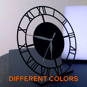 May include: Black metal clock with Roman numeral markings on the face. The clock is on a stand and has a black background with white hands.