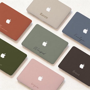 Peut inclure: Une collection de sept coques pour ordinateur portable dans diverses couleurs mates, notamment terre cuite, beige, bleu ardoise, vert olive, brun foncé et rose poudré. Chaque coque présente un logo Apple blanc central et un prénom personnalisé.