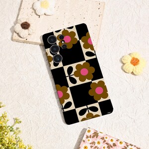 May include: A black and white checkered phone case with a retro floral pattern. The case features brown flowers with pink centers. The phone case has a camera array on the upper left side.