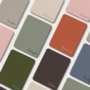 May include: A collection of rectangular, solid-colored covers in shades of sage green, terracotta, dark brown, dusty pink, olive green, slate blue, and beige. Each cover features a unique name printed in a cursive script, including Tuesday, Cassia, Paloma, Winifred, Beatrice, Joyce, Chloe, and Evelyn.