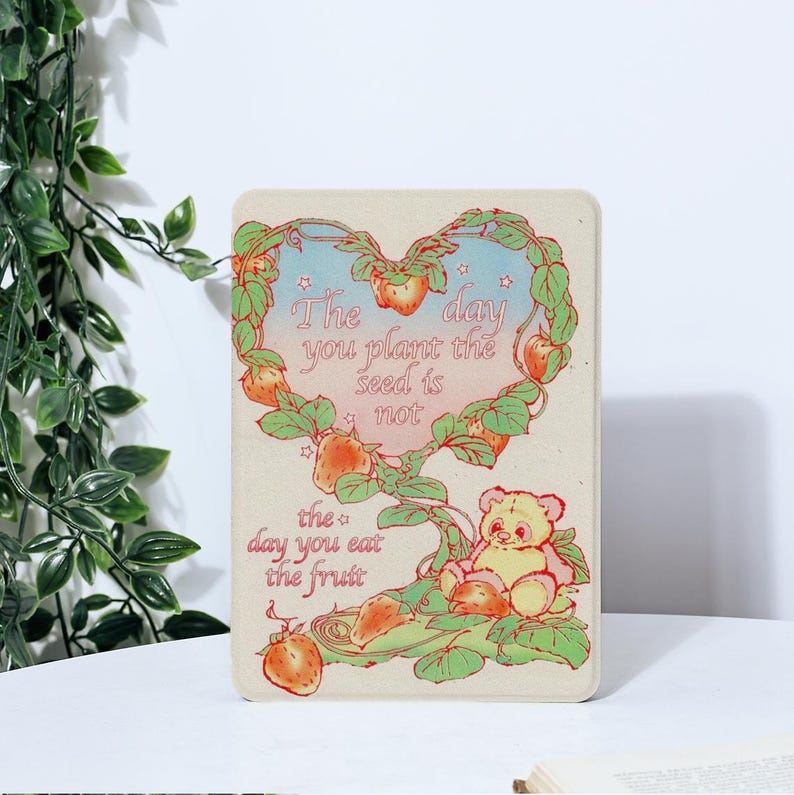 May include: A heart-shaped illustration of a strawberry plant with a quote: "The day you plant the seed is not the day you eat the fruit." A cartoon bear sits on a branch of the plant.