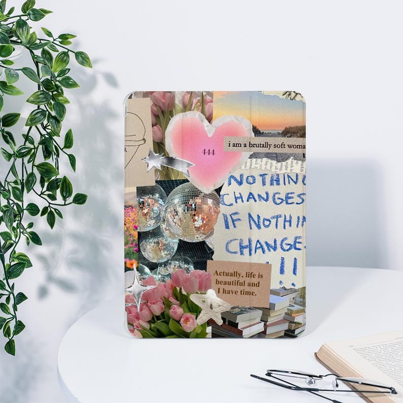 May include: A decorative tablet case featuring a collage design. The design includes a pink heart, disco balls, pink flowers, and text that reads "NOTHING CHANGES IF NOTHING CHANGE." The case has a soft, feminine aesthetic.