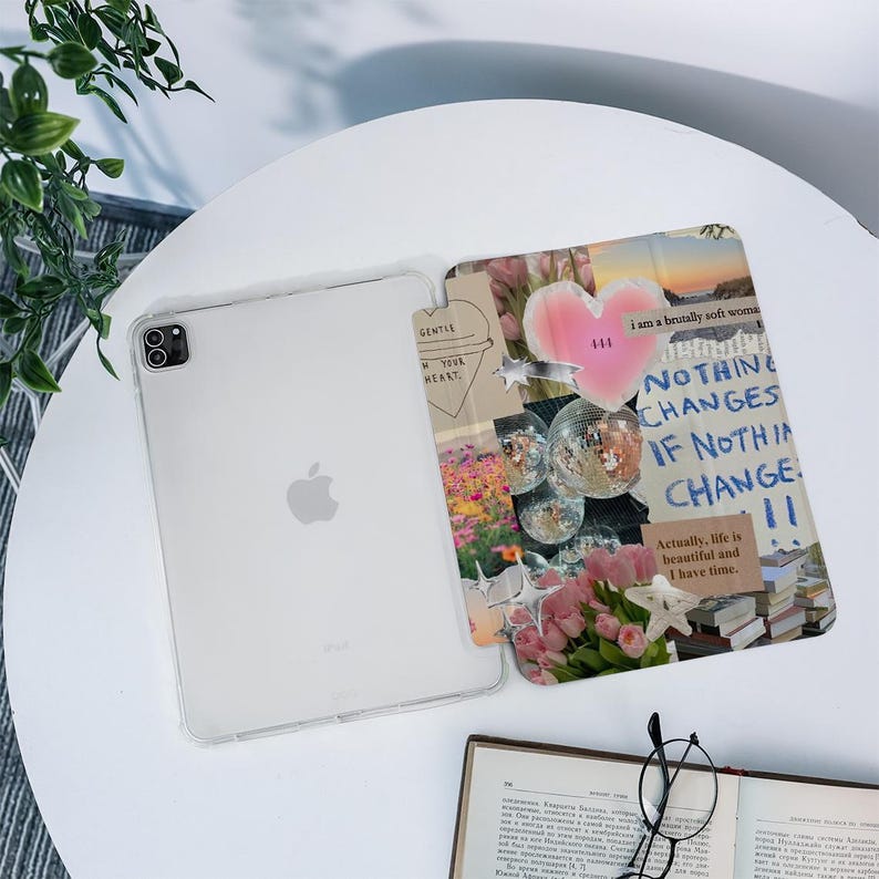 May include: A clear iPad case with a collage design. The collage includes a pink heart, disco balls, flowers, and text that reads "NOTHING CHANGES IF NOTHIN CHANGE". The text "GENTLE MY HEART" is also visible.