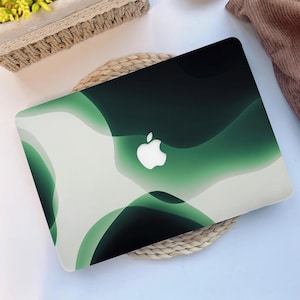 May include: A laptop with a green and white abstract design. The cover features a gradient of green hues with a white Apple logo in the center. The design has a flowing, wave-like pattern.