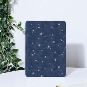 Puede incluir: Una funda para tableta azul marino con un patrón de pequeñas estrellas de color claro. La funda tiene esquinas redondeadas y una superficie lisa. El fondo es blanco, con vides verdes a la izquierda.