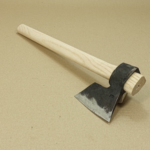Könnte beinhalten: Eine Axt mit schwarzem Griff und einem Holzstiel. Die Axtkopf ist leicht gebogen und hat eine scharfe Kante. Der Stiel ist aus hellem Holz und hat eine leichte Verjüngung.