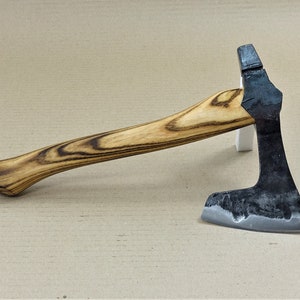Könnte beinhalten: Eine kleine Axt mit einem Holzstiel und einem schwarzen Metallkopf. Der Stiel hat ein dunkles Holzmaserungsmuster.