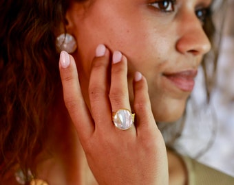 May include: A gold ring with a large, round, white mother-of-pearl stone.