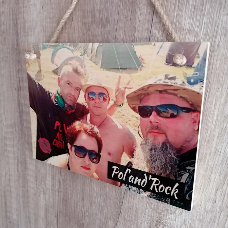 May include: A wooden sign with a photo of four people at a music festival. The sign has the text "Pol'and' Rock" printed on it.