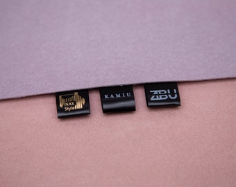 May include: Three black fabric labels with white text. The labels read "IN.KE Style", "KAMIU", and "ZBU".