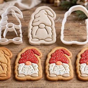 May include: A set of white plastic gnome cookie cutters and stamps, including a plain dough cutout and three finished cookies decorated with red icing hats and white icing beards. Text at the bottom reads: Gnome Cookie Cutter, Food Safe PLA, 6cm 8cm, Cutter + Stamp.