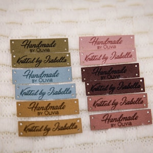 May include: A set of eight brown, pink, and blue leather labels with the text "Handmade by Olivia" and "Knitted by Isabella" in a cursive font.