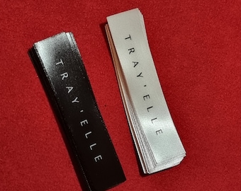 May include: Two stacks of fabric labels with the text "TRAY.ELLE" printed on them. One stack is black and the other is white.