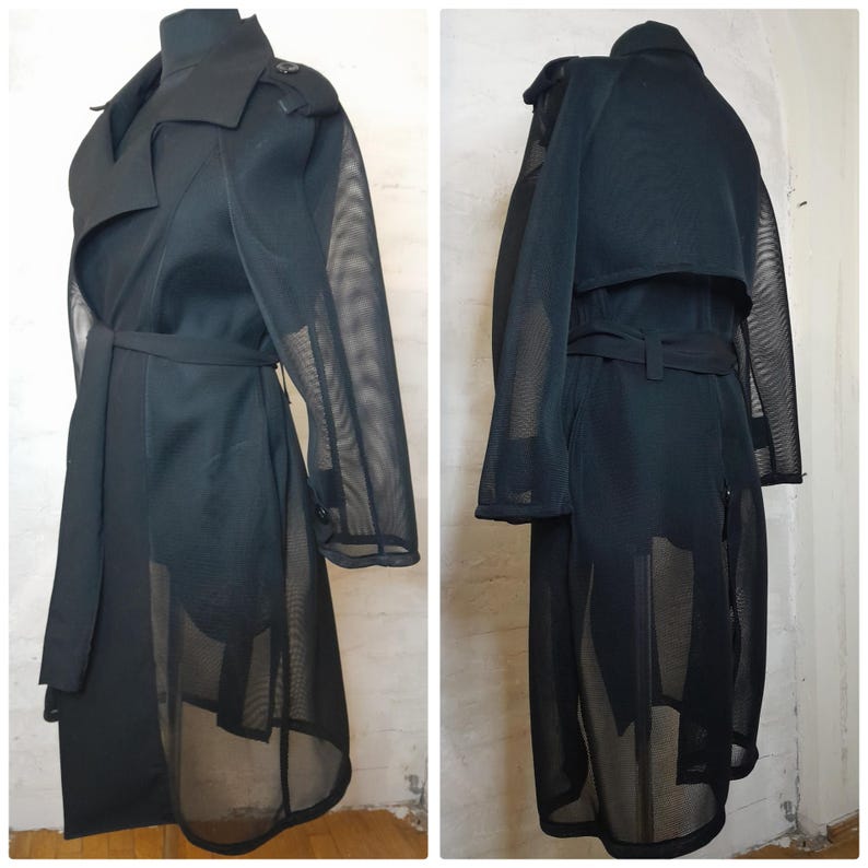 May include: A black mesh trench coat with a long, flowing silhouette. The coat has a classic trench coat design with a collar, belt, and pockets. The mesh fabric gives the coat a sheer and airy look.