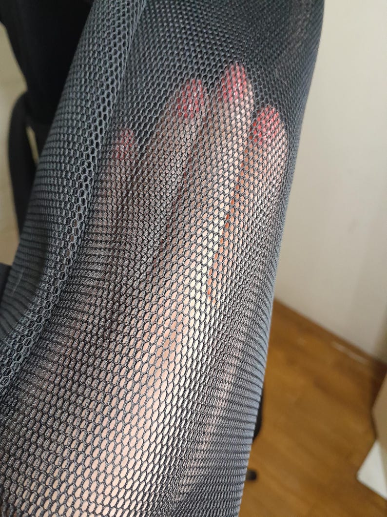 May include: Close-up of black mesh fabric with a fine, even weave. The fabric is soft and flexible, and it has a slightly textured surface.