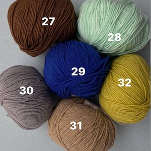 May include: Six balls of yarn in different colors: brown, green, blue, gray, beige, and yellow. Each ball is labeled with a number from 27 to 32.