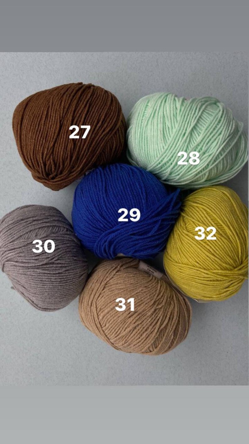 May include: Six balls of yarn in different colors: brown, green, blue, gray, beige, and yellow. Each ball is labeled with a number from 27 to 32.