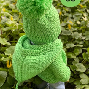 May include: A bright green knitted hat with a pom-pom on top and a matching green knitted scarf. The hat and scarf have a tassel detail. The number 35 is written on a green circle in the background.