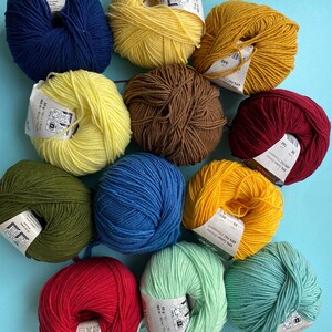 May include: Ten balls of yarn in various colors, including red, green, blue, yellow, and brown. Each ball has a label with text in a foreign language.