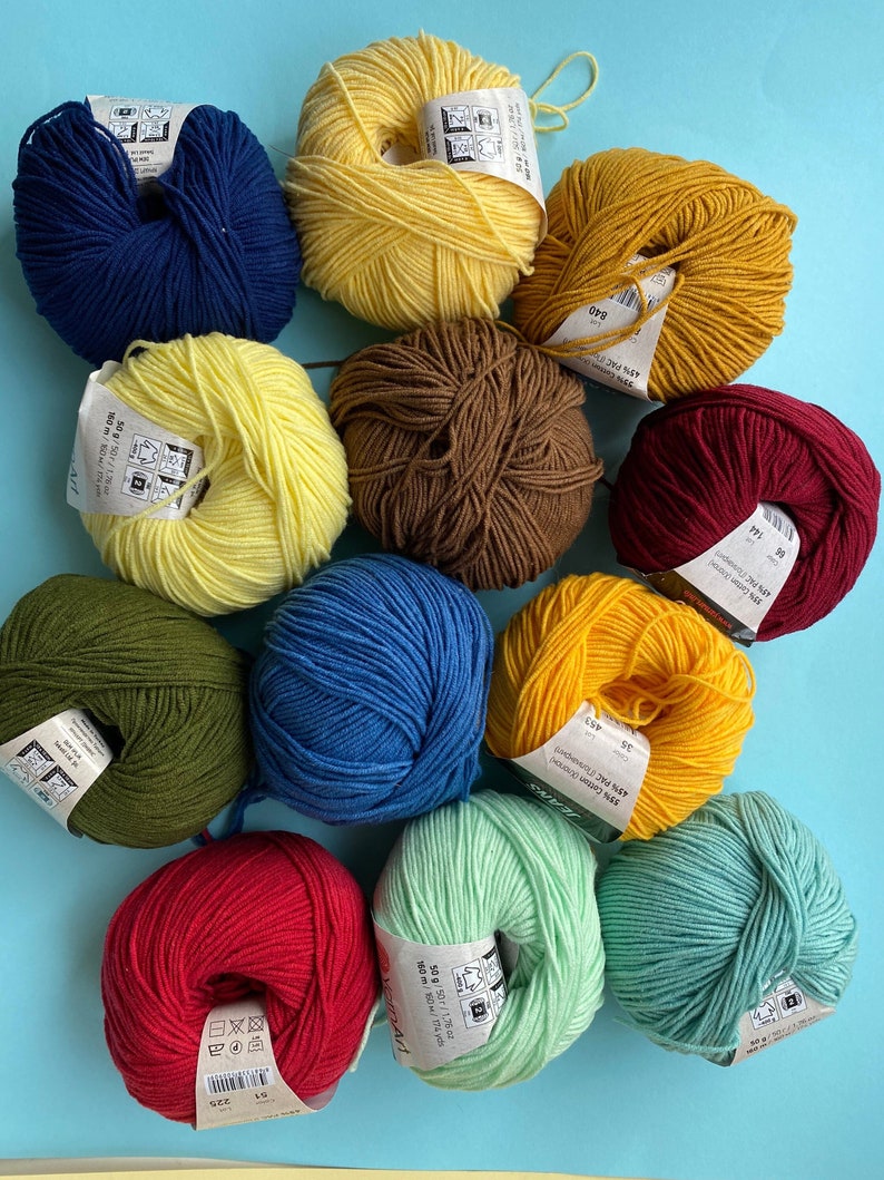 May include: Ten balls of yarn in various colors, including red, green, blue, yellow, and brown. Each ball has a label with text in a foreign language.