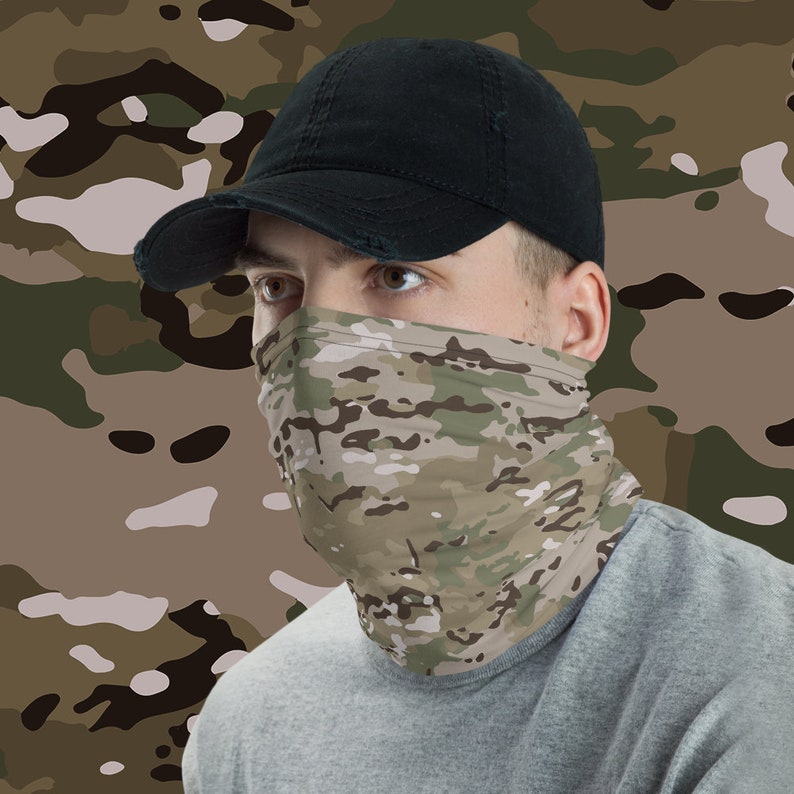 May include: A person wearing a black baseball cap and a camouflage face mask. The mask is a multi-colored pattern of green, brown, and tan.