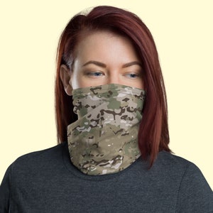 May include: A person wearing a camouflage face mask. The mask is made of a soft, breathable fabric and is designed to cover the nose and mouth.