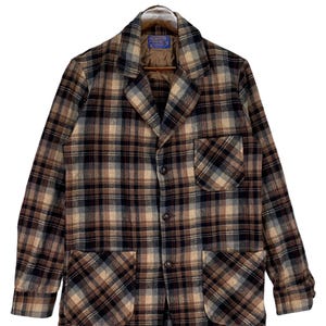 May include: A vintage plaid blazer in shades of brown, black, and beige. The jacket features a classic notched collar, two front pockets, and a three-button closure. The blazer is hanging on a wooden hanger.