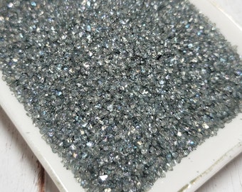 May include: A white square dish filled with iridescent silver glitter. The glitter is a fine, sparkly texture.