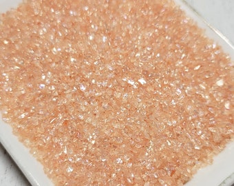 May include: A white square dish filled with peach-colored iridescent glitter.