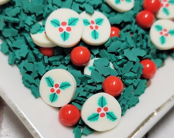 May include: White and green sprinkles with a holly design and red round sprinkles on a white plate.
