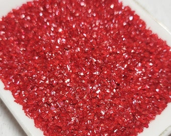 May include: A white square dish filled with red sparkling sugar crystals.