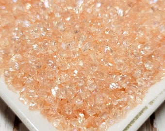 May include: A white ceramic dish filled with iridescent peach-colored glitter. The glitter is small and has a pearlescent finish.