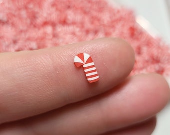 May include: A small red and white candy cane charm, perfect for adding a festive touch to crafts and jewelry.