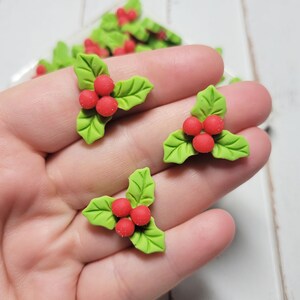 May include: Green holly leaf charms with red berries. The charms are made of polymer clay and are perfect for adding a festive touch to your crafts.