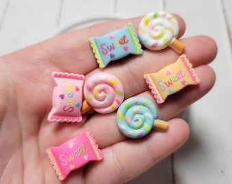 May include: Six colorful candy charms with a swirl design and the word "Sweet" on each. The charms are made of polymer clay and are perfect for adding a touch of whimsy to your crafts.