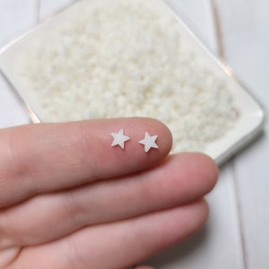 May include: Two small white star-shaped embellishments on a finger.