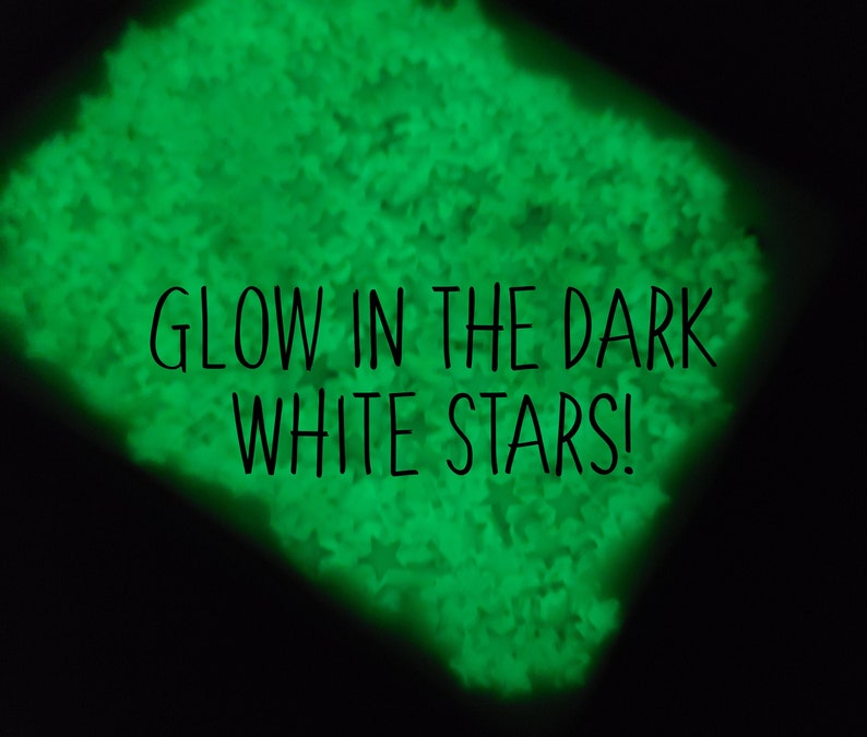 May include: A close-up of a pile of white glow-in-the-dark stars. The stars are glowing green in the dark. The text "GLOW IN THE DARK WHITE STARS!" is superimposed on the image.